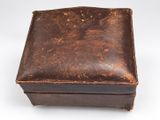an old leather box sitting on top of a white surface