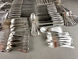 many forks and spoons laid out on a table