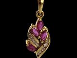 a gold pendant with pink stones and diamonds on a black background