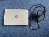 un ordinateur portable posé sur un tapis bleu, avec un chargeur branché dessus