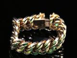 un gros plan d'un bracelet doré et vert posé sur une surface noire