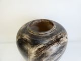 un vase noir et blanc posé sur une surface blanche
