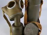 un vieux masque à gaz et une cartouche posés sur une surface blanche