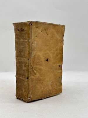 un vieux livre posé sur une table blanche à côté d'un mur blanc