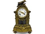 une horloge en or surmontée d'un oiseau