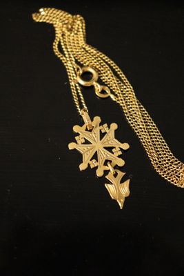 a close up of a gold necklace with a cross on it