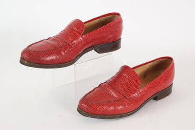 pair of red loafers on clear acrylic stand on white background