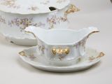 a white and gold tea set with a saucer and a cup