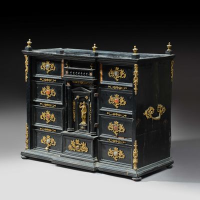 une commode ancienne noire et dorée, surmontée d'une horloge