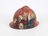 a red hard hat with gold paint on it on a white surface