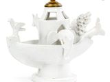 a white vase with a bird on it and a lamp on top of it