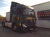 un gros camion vert garé devant un immeuble