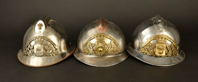 trois casques de pompier posés les uns à côté des autres sur une table