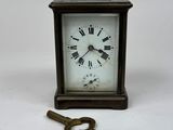 a small clock and a key on a white surface