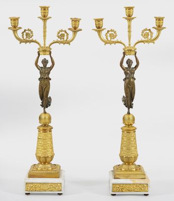 a pair of antique brass candlesticks on marble bases