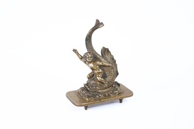 brass figurine of a fish on a stand with a white background