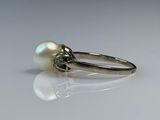 an image of a white pearl and diamond ring on a white surface