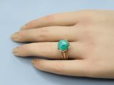 a close up of a person ' s hand wearing a ring with a green stone on it