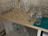 bottles and glasses on a shelf in a kitchen with tiled walls
