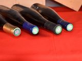 four bottles of wine are lined up on a red table