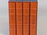 trois livres orange empilés les uns sur les autres sur une surface blanche