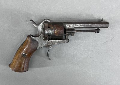 un vieux revolver avec une poignée en bois sur une surface blanche