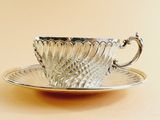 a silver cup and saucer sitting on a saucer