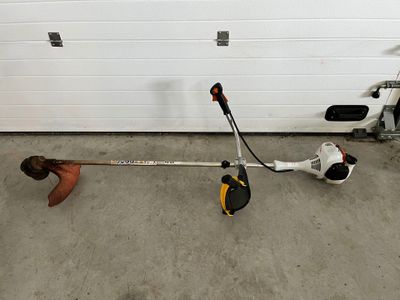 un homme en train de réparer une débroussailleuse dans un garage