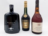 trois bouteilles d'alcool sont alignées sur une surface blanche