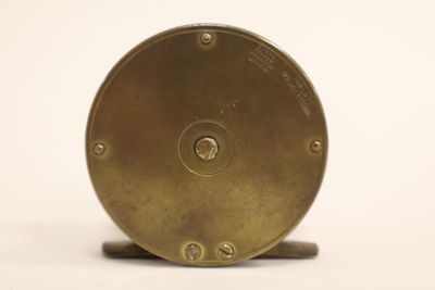 a small brass clock on a stand on a white surface