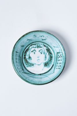 une petite assiette bleue sur laquelle est représentée une femme