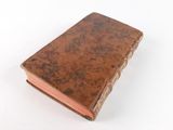 an old book with a brown cover sitting on top of a white surface