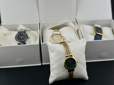 trois montres dans un coffret blanc, avec une chaîne dorée autour du bracelet