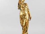 une image représentant une statue en or d'une femme tenant un oiseau