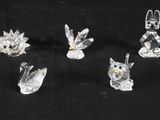 six figurines en verre transparent représentant des animaux et des oiseaux sur fond noir