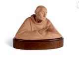 statue d'un moine assis sur un socle en bois, sur fond blanc