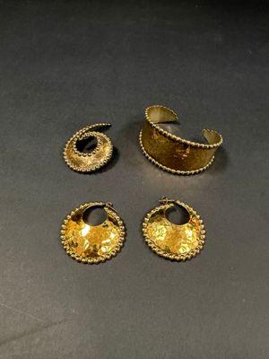 three pieces of gold jewelry sitting on top of a table