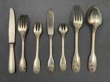 six forks and a knife are lined up on a table