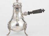une cafetière ancienne en argent, munie d'une anse et posée sur un socle