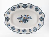 des fleurs bleues et orange disposées sur un plateau blanc, sur fond blanc