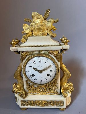 a white clock with a gold decoration on it