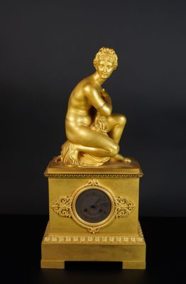 une image représentant une statue en or d'un homme assis au sommet d'une horloge
