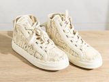 beige lace high top sneakers on wooden table with white background