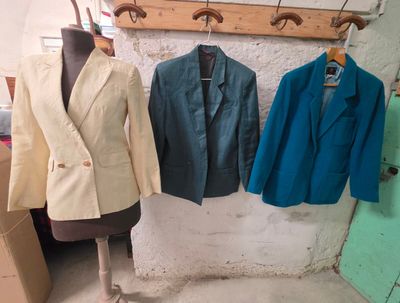 trois vestes suspendues à un porte-vêtements dans une pièce