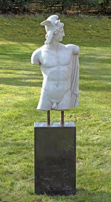 une statue représentant un homme debout sur un socle, dans l'herbe