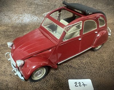 une petite voiture rouge sur laquelle est posée une valise