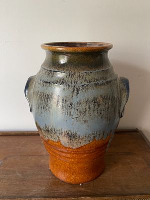 un vase bleu et marron posé sur une table en bois