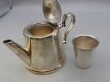 a silver tea pot and two cups sitting on a table