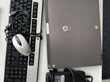 un ordinateur portable et une souris posés sur un bureau, à côté d'un clavier et d'une souris