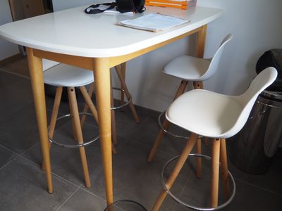 une table blanche avec deux chaises et un ordinateur portable posé dessus